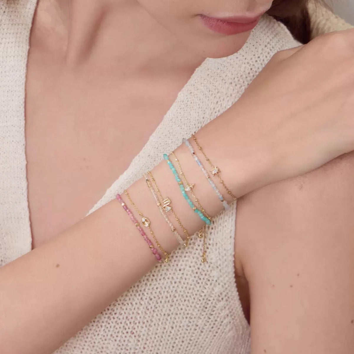 Close-up of a person wearing multiple bracelets on a light background