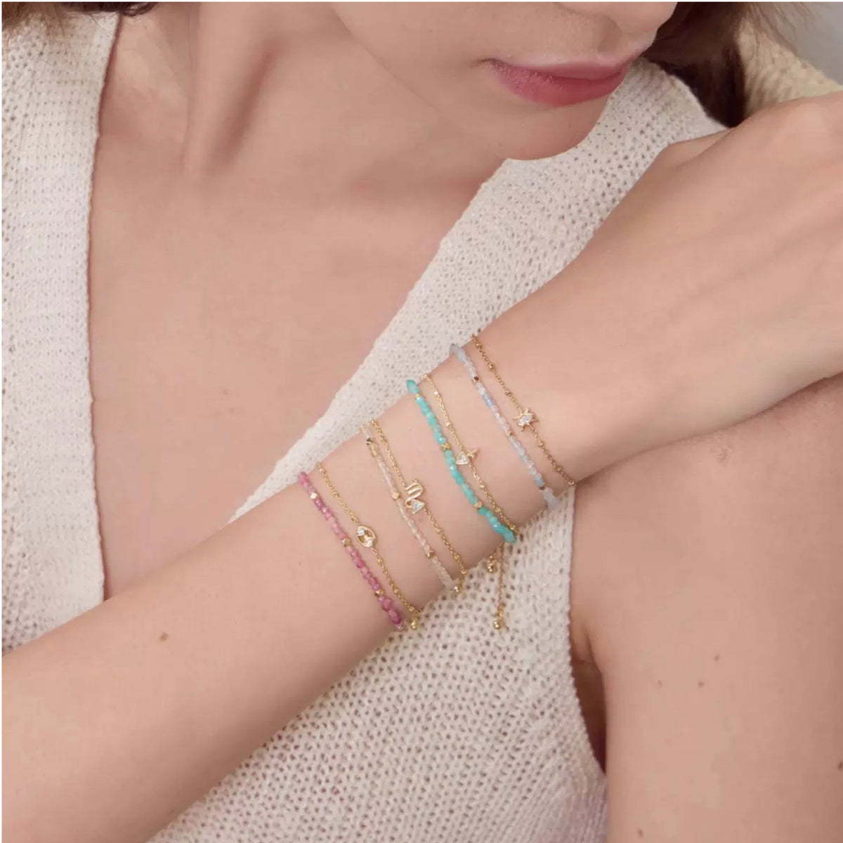 Close-up of a person wearing multiple bracelets on a light background