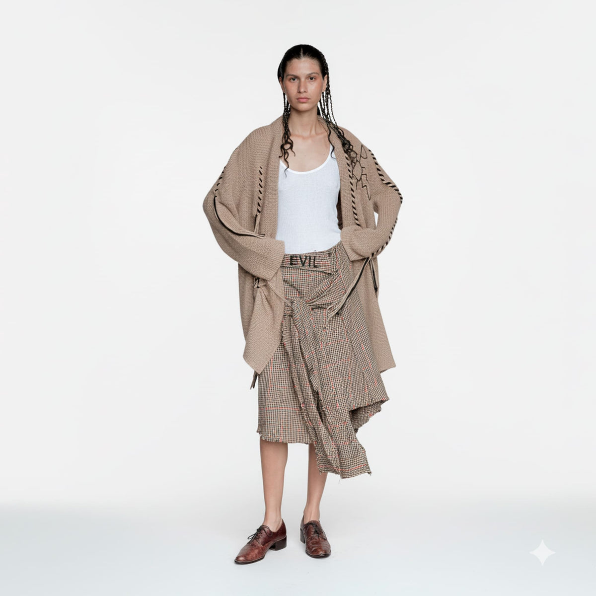 Woman wearing a beige cardigan and plaid skirt on a white background