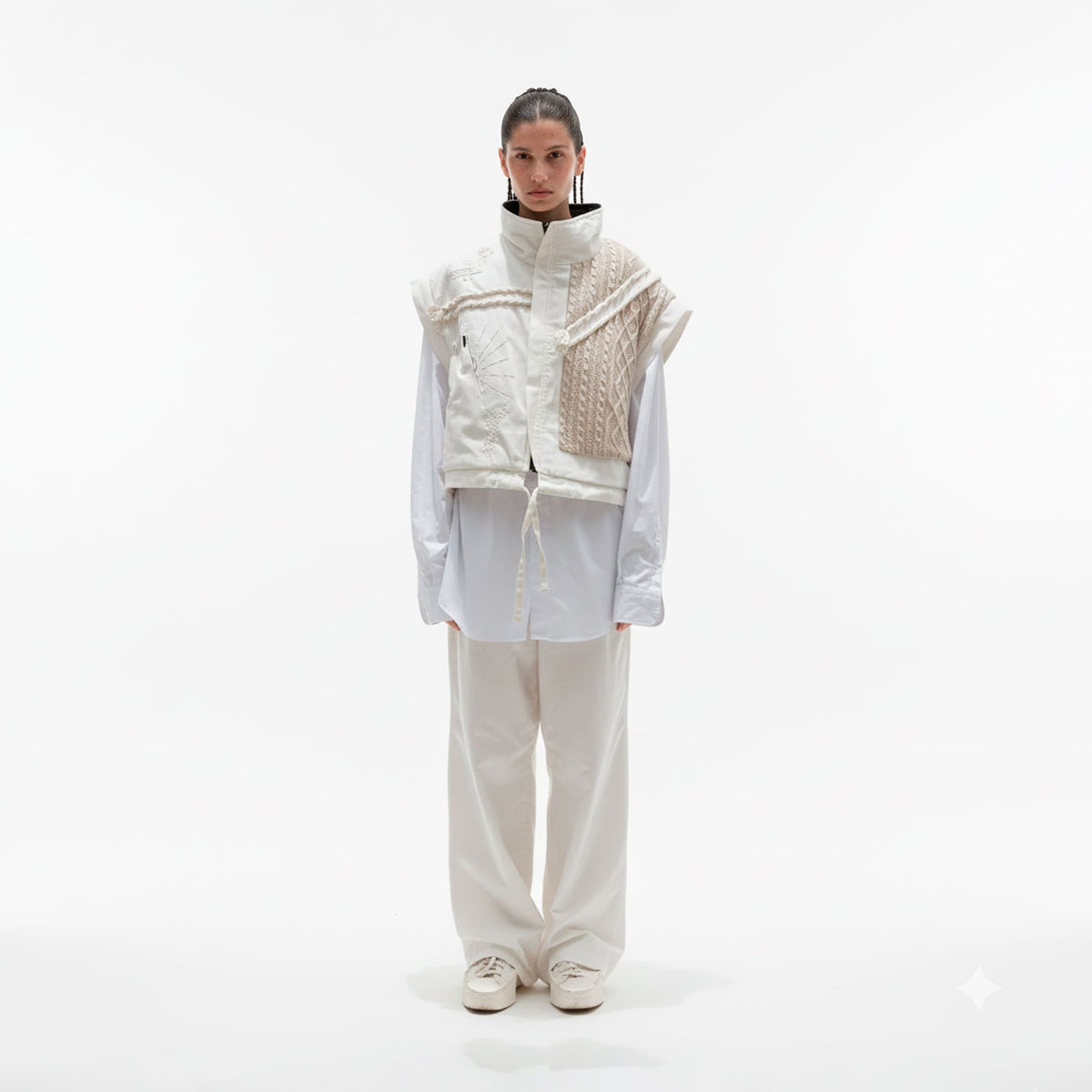 Person wearing a white outfit with a textured vest on a white background