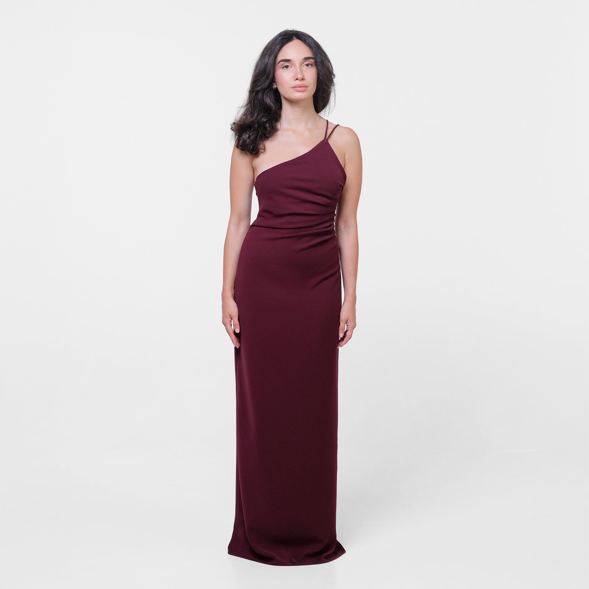 Woman wearing a burgundy one-shoulder dress on a white background