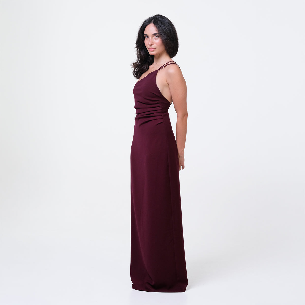 Woman wearing a burgundy one-shoulder dress on a white background