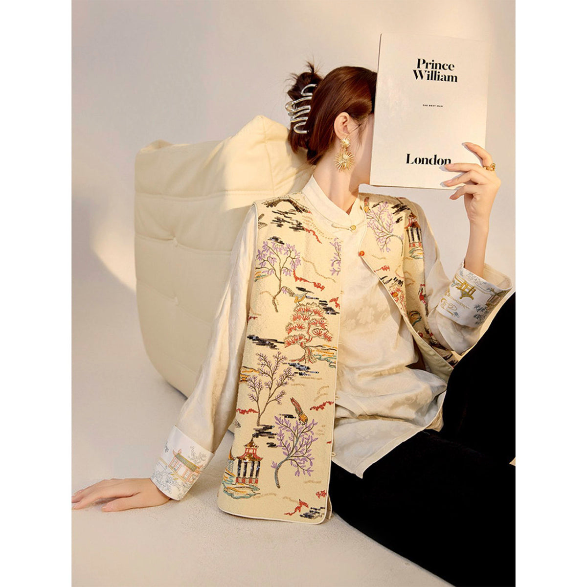 Person wearing a traditional embroidered garment holding a 'Prince William' book