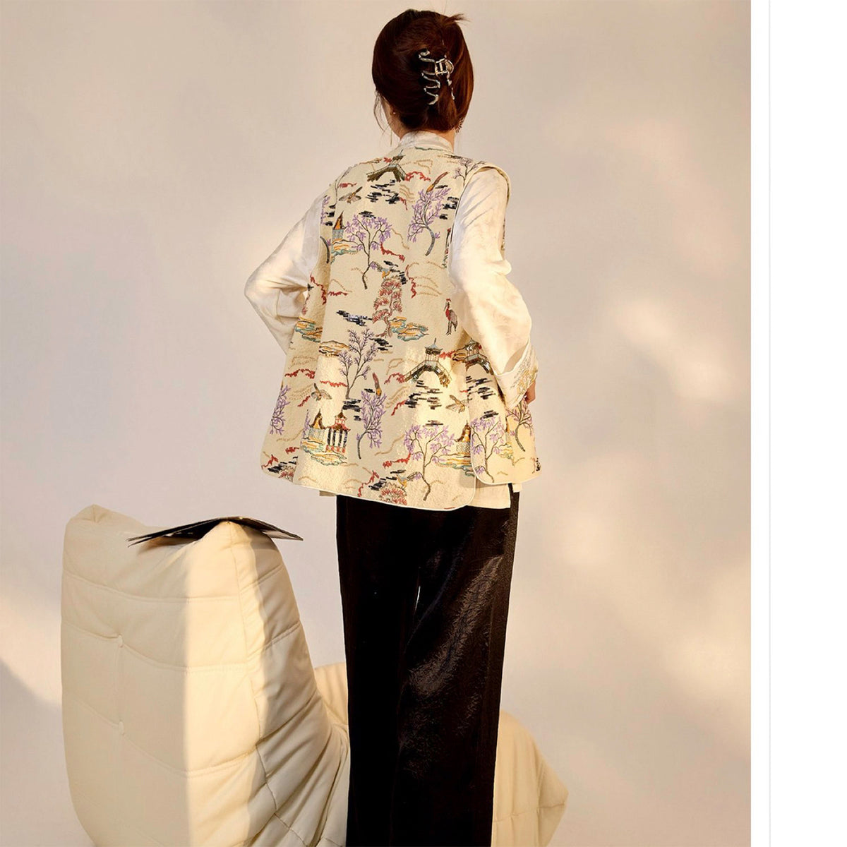 Person wearing a traditional embroidered jacket with a plain background