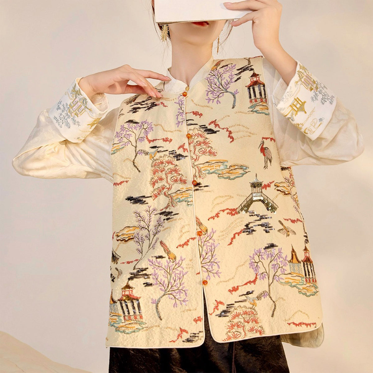 Person wearing a traditional embroidered jacket with intricate designs on a plain background