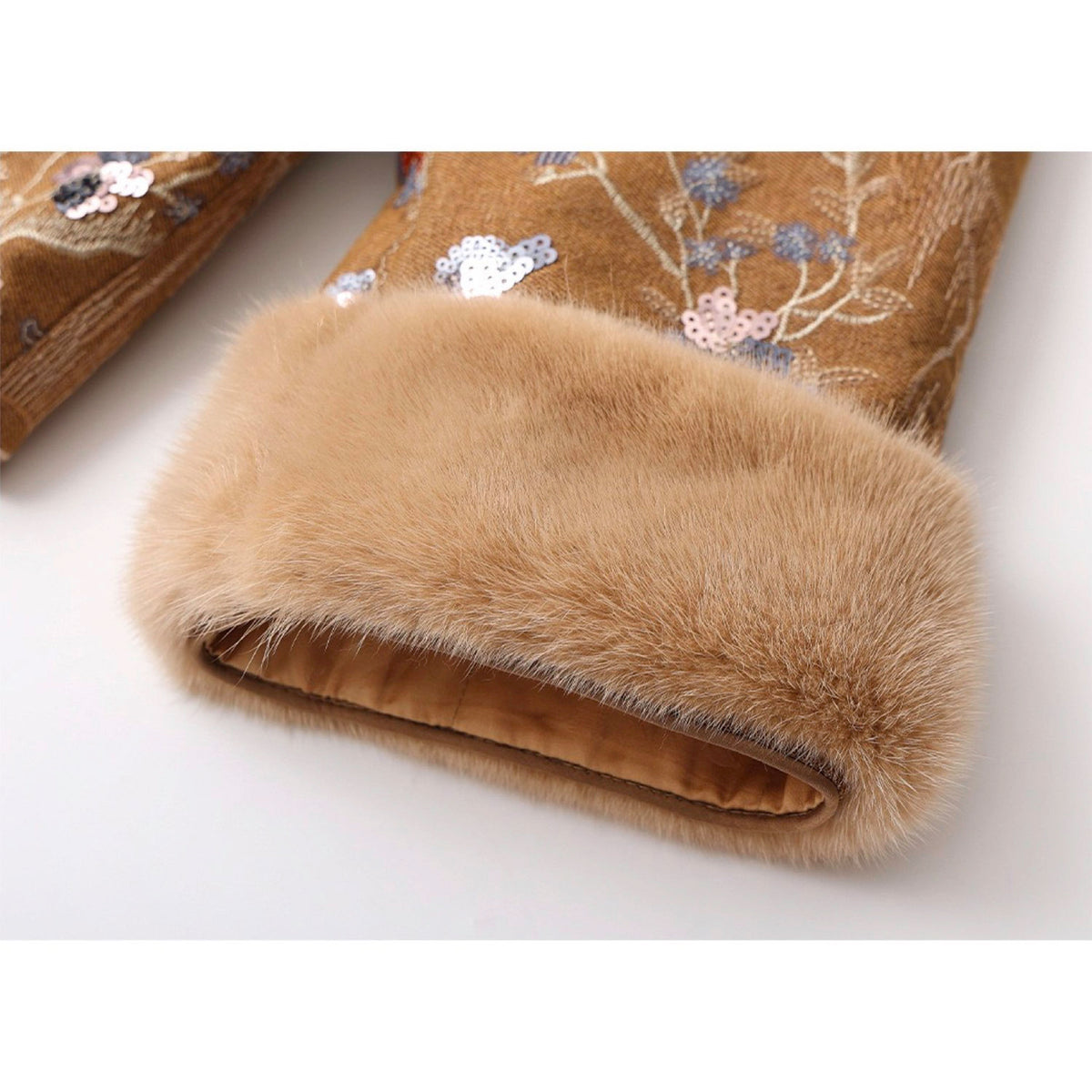Folded brown fur garment with floral embroidery on a white background