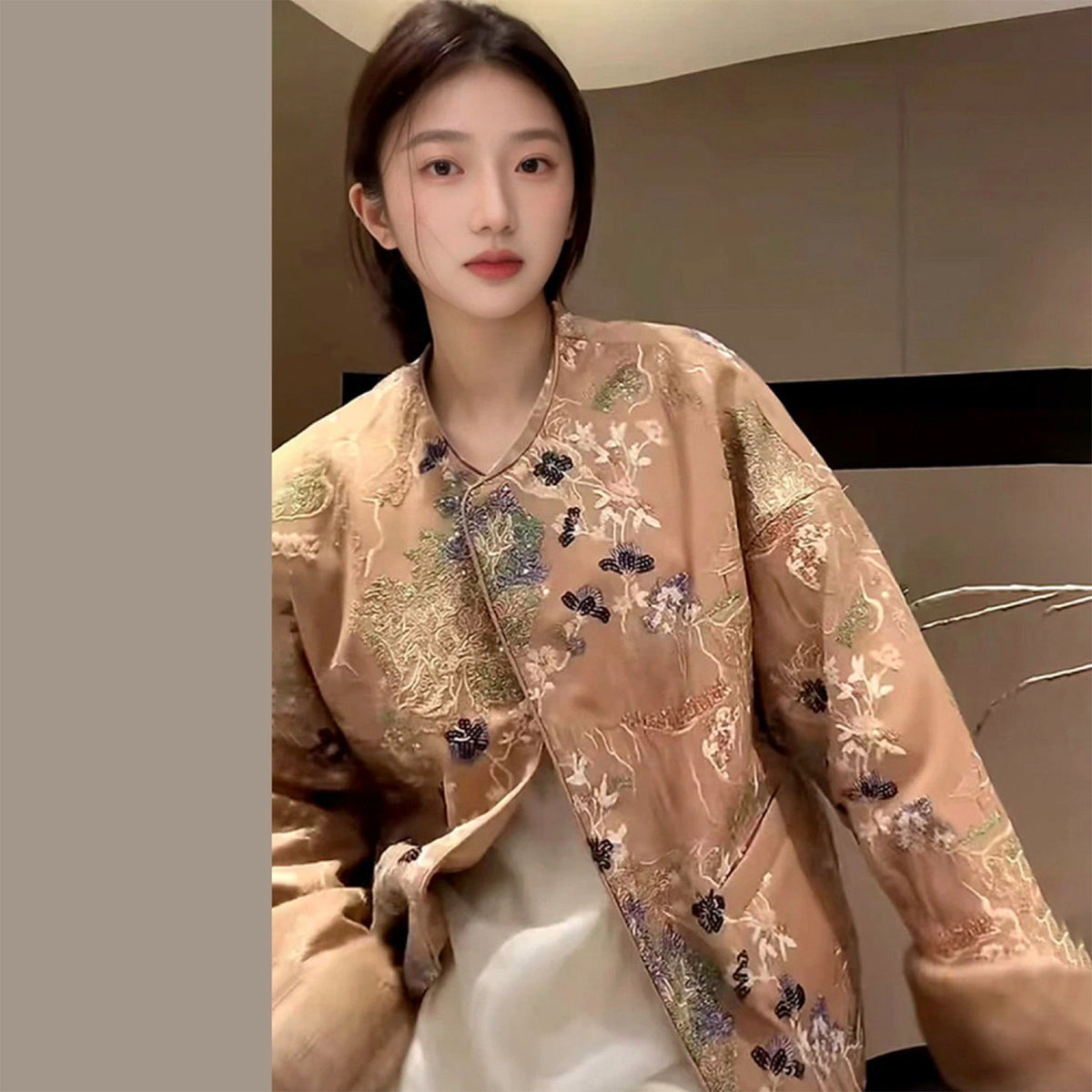 Woman wearing an embroidered beige jacket in a neutral setting