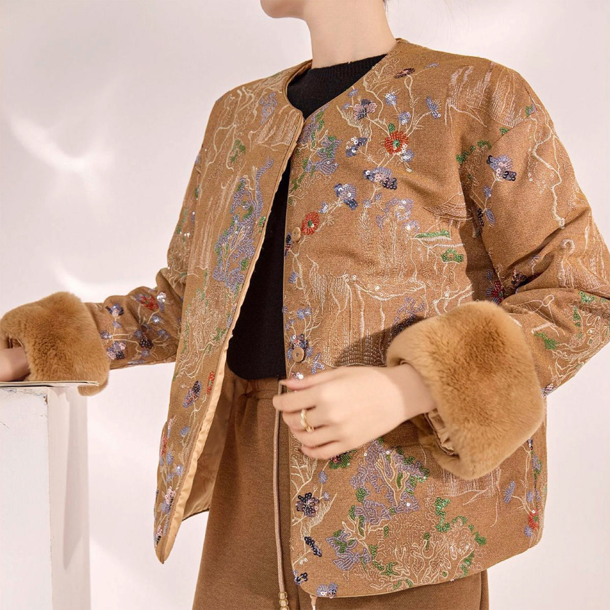 Mannequin wearing a brown embroidered jacket with fur cuffs on a white background