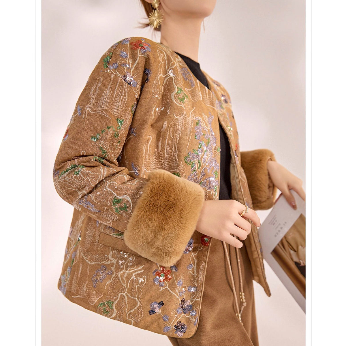 Mannequin wearing a brown embroidered jacket with fur cuffs on a plain background