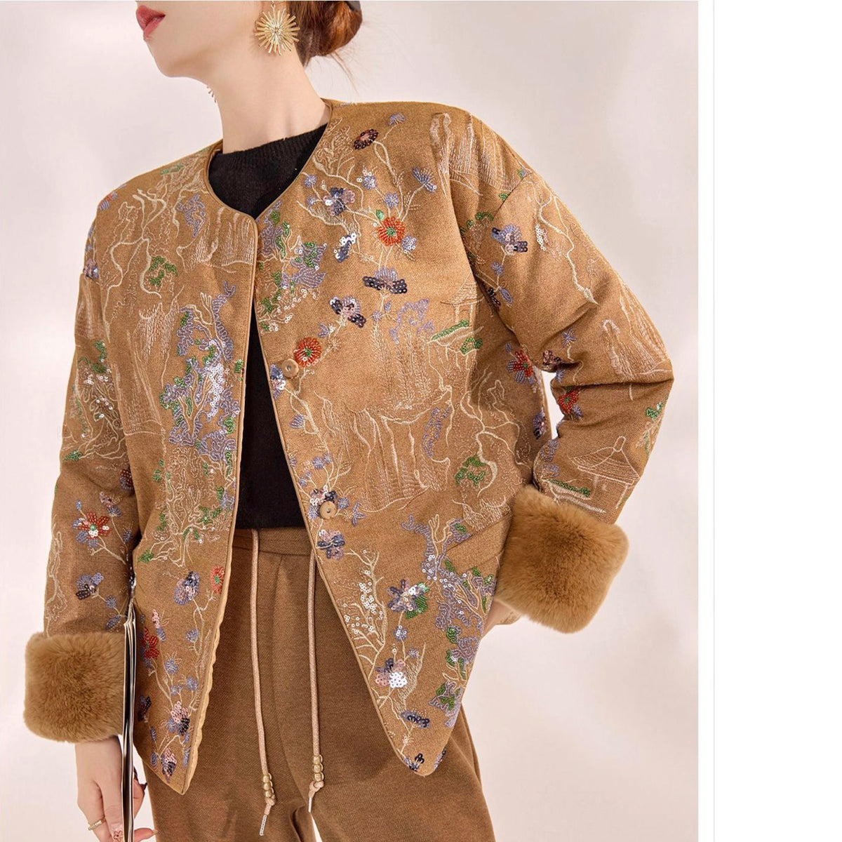Beige embroidered jacket with fur trim on a mannequin against a plain background