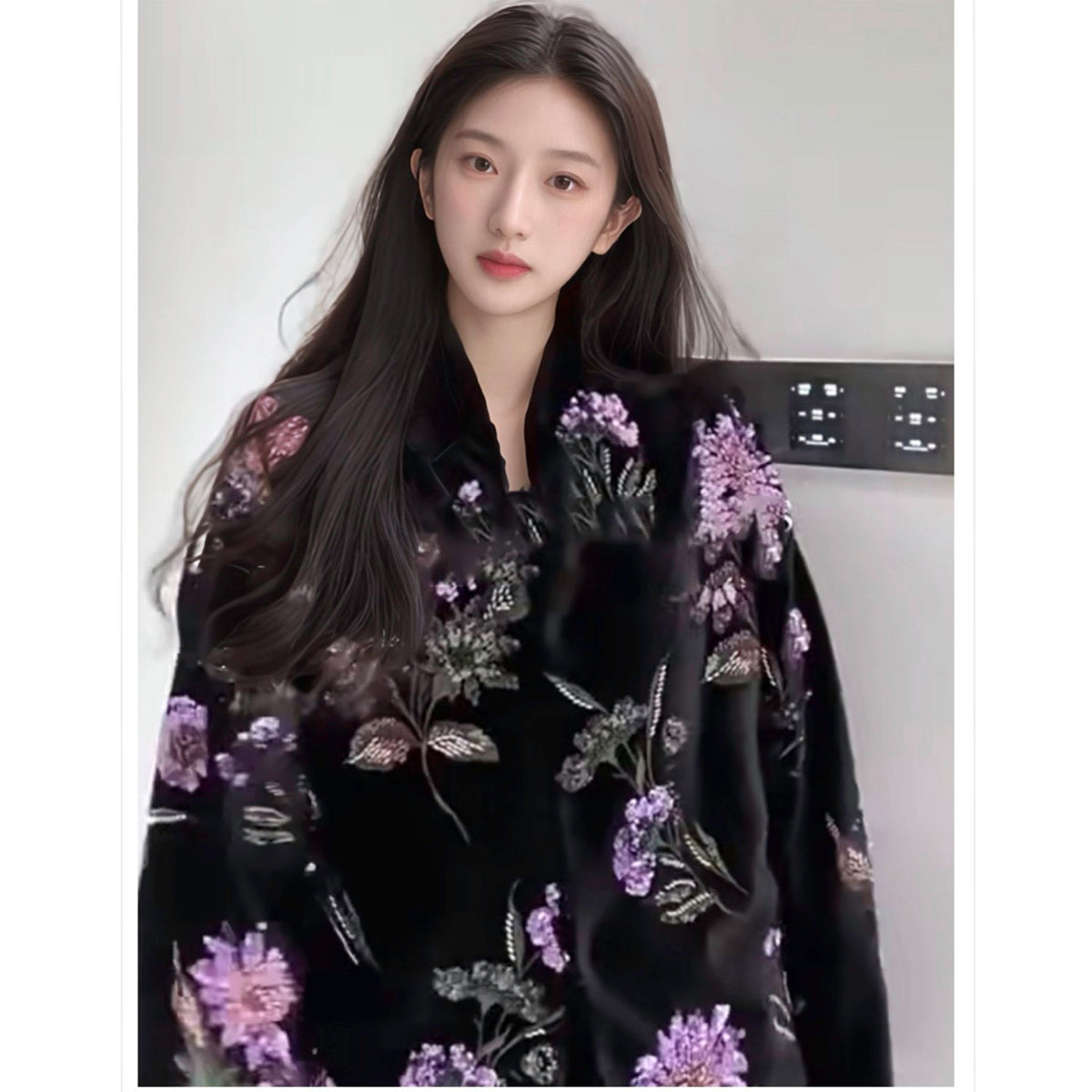 Woman wearing a black floral dress with purple flowers against a plain background