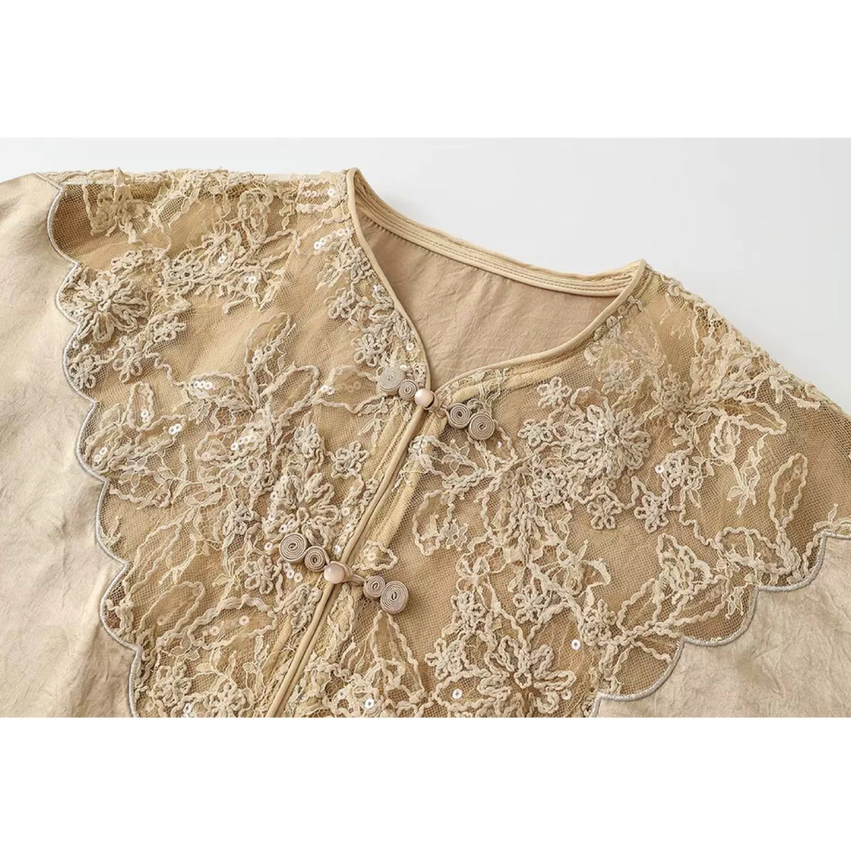 Beige lace garment with floral patterns on a white background