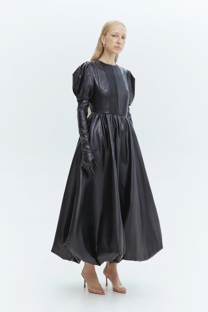 Woman wearing a black dress with long sleeves and gloves on a white background