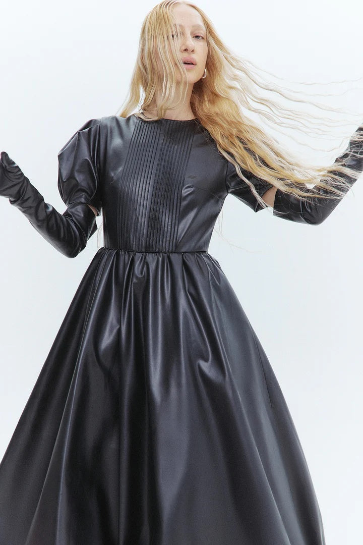 Woman wearing a black dress with sheer sleeves against a white background