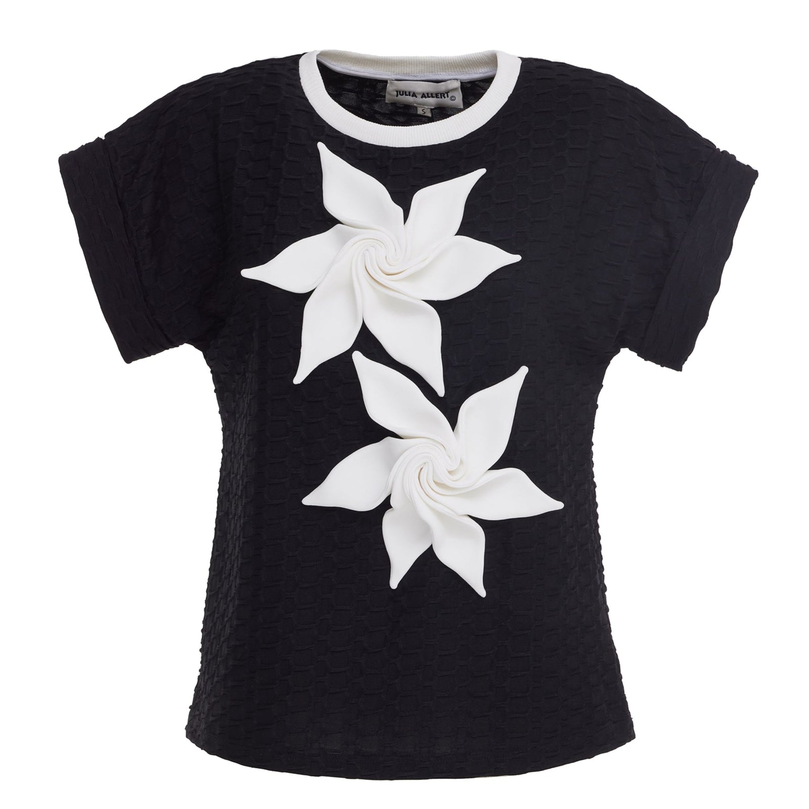 The JULIA ALLERT Black Short Sleeve Top With Floral Detail features structured fabric and two large white 3D pinwheel flowers on the front.