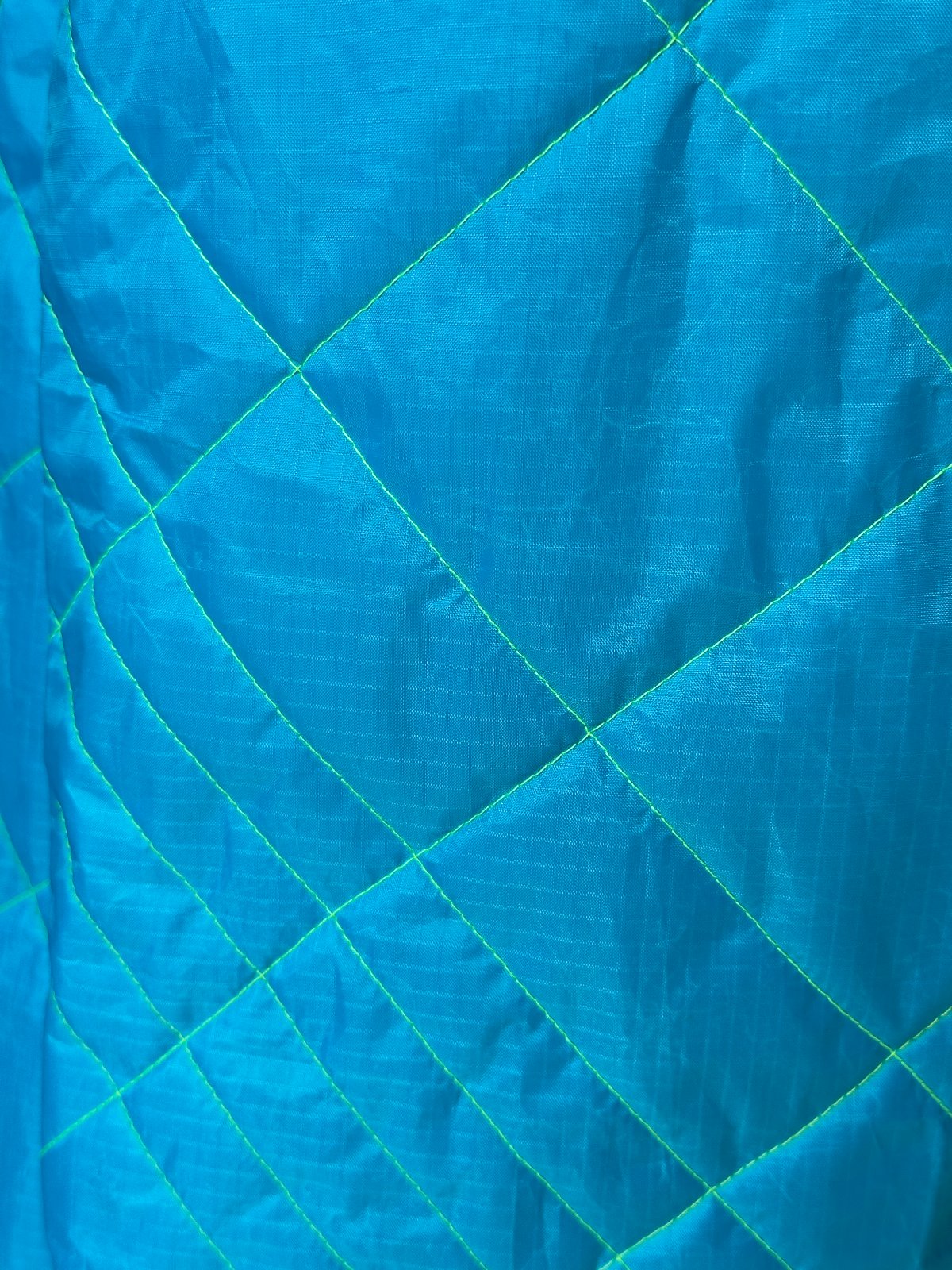STUDIO WUNDERBAR Kite Classic: electric blue diamond-quilted maxi coat with neon green lapels and black-and-white graphic accents, women's and men's upcycled long coat, close-up detail, buy at DOORS NYC