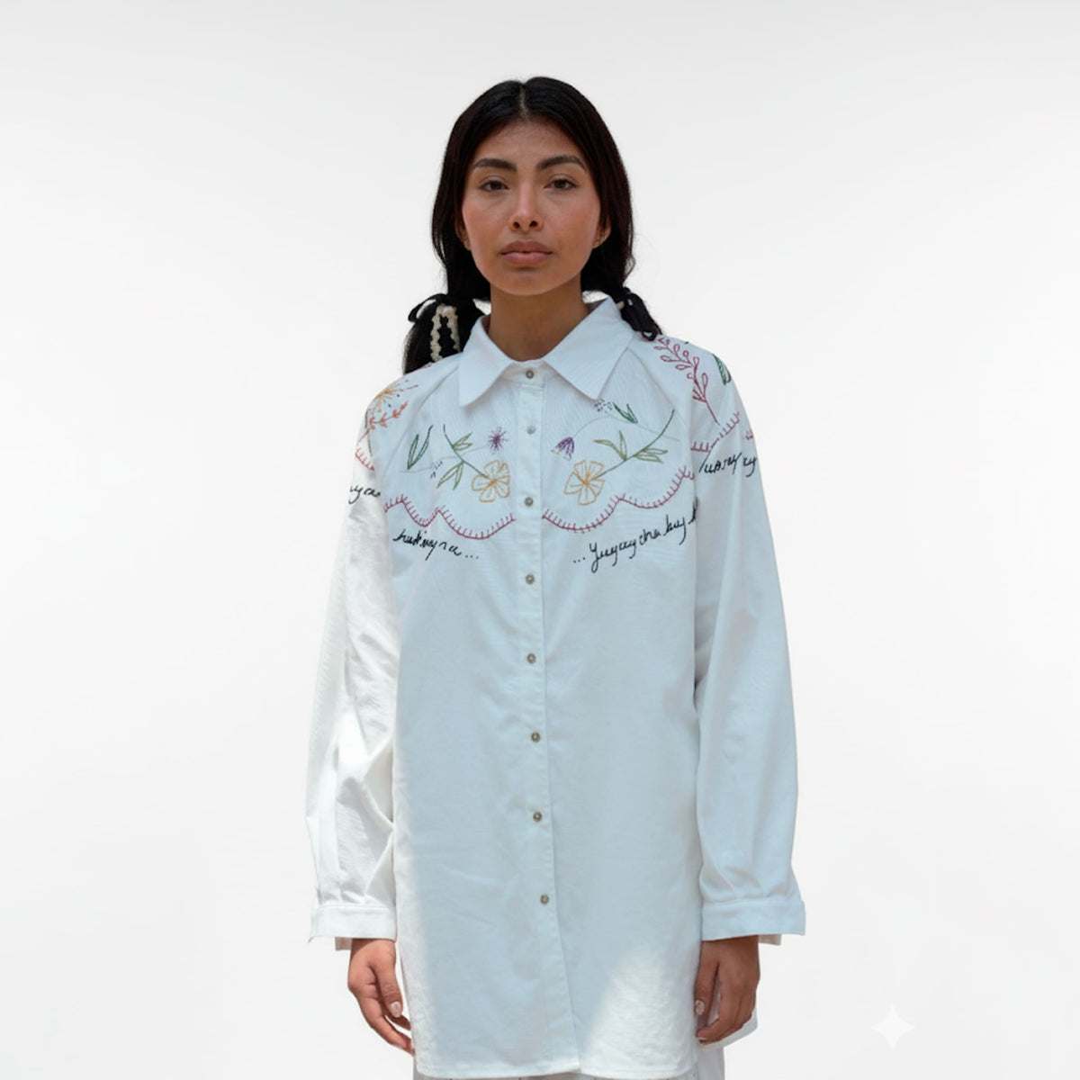 Woman wearing a light blue embroidered shirt on a white background