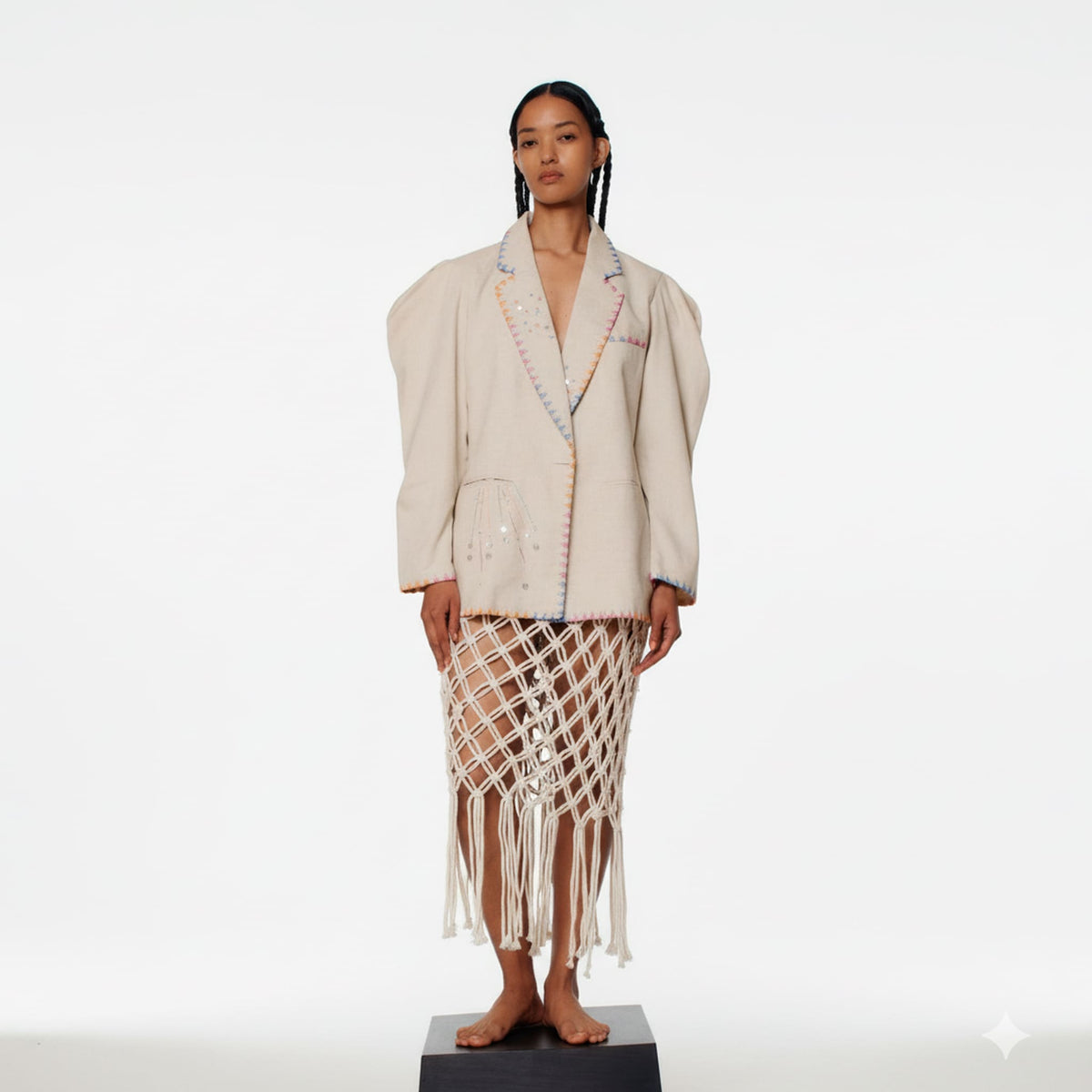 Woman wearing a beige jacket and a patterned skirt on a white background