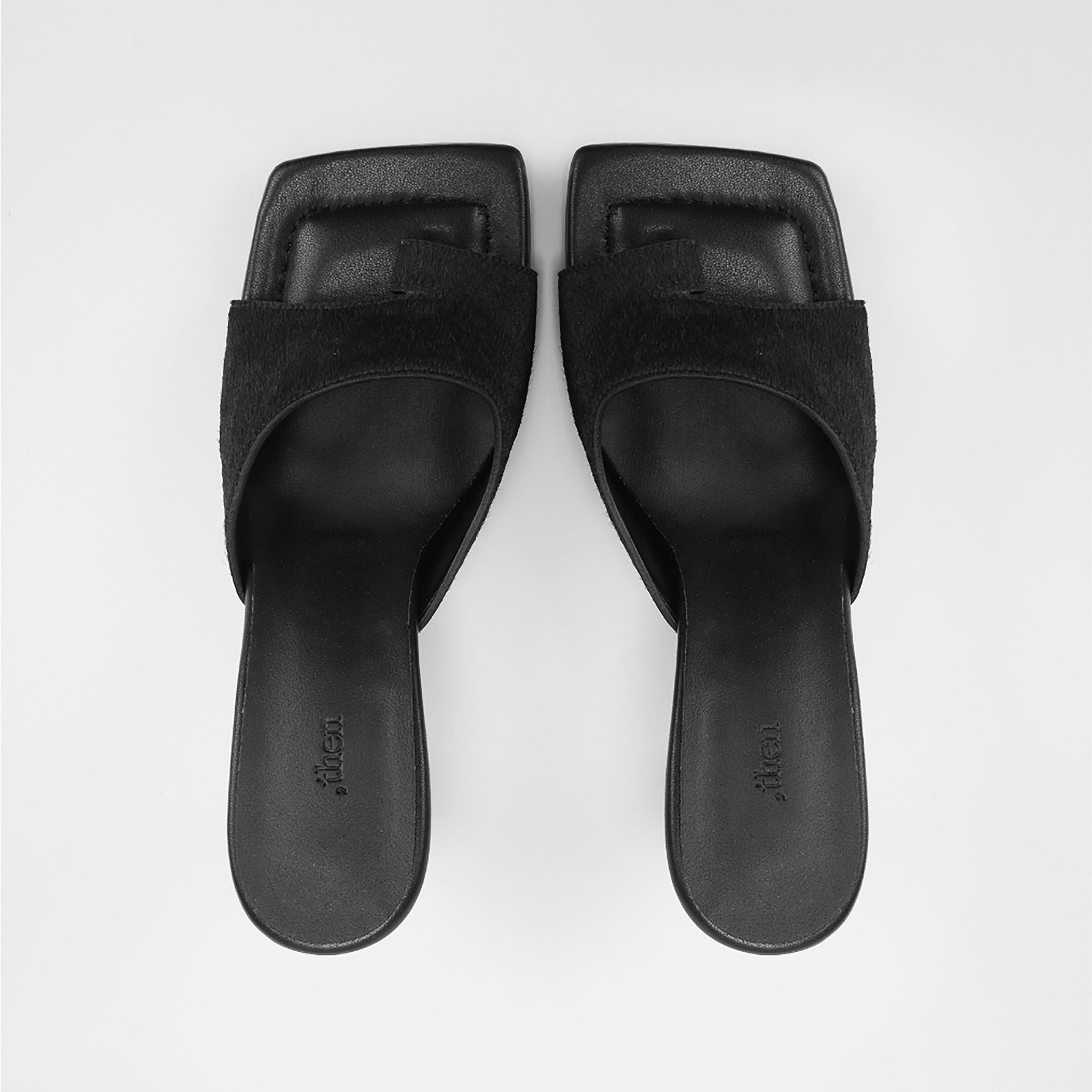 A pair of THEN Black Suede Toe-Ring Heeled Mules, handcrafted in Korea with square toes and low heels, are placed side by side on a white background.