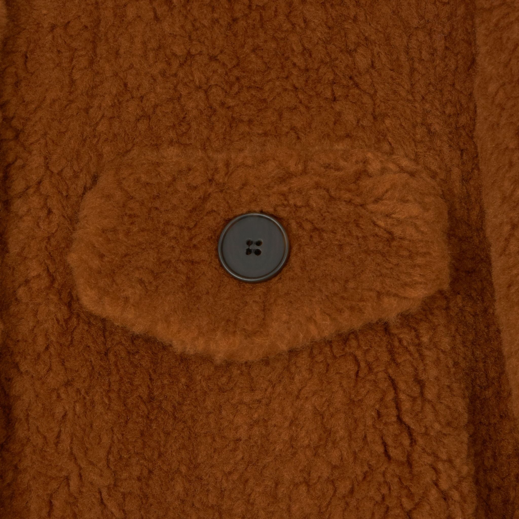 Close-up of the Ethereal Fur Jacket with soft fleece fabric, showcasing its brown, textured, fuzzy design and a single black button on a flap pocket—perfect for adding warmth and style to your winter layers.