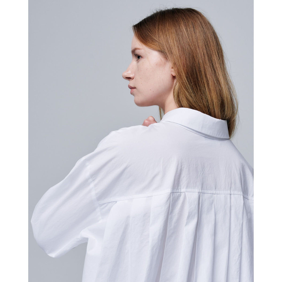 Woman wearing a white shirt against a plain background