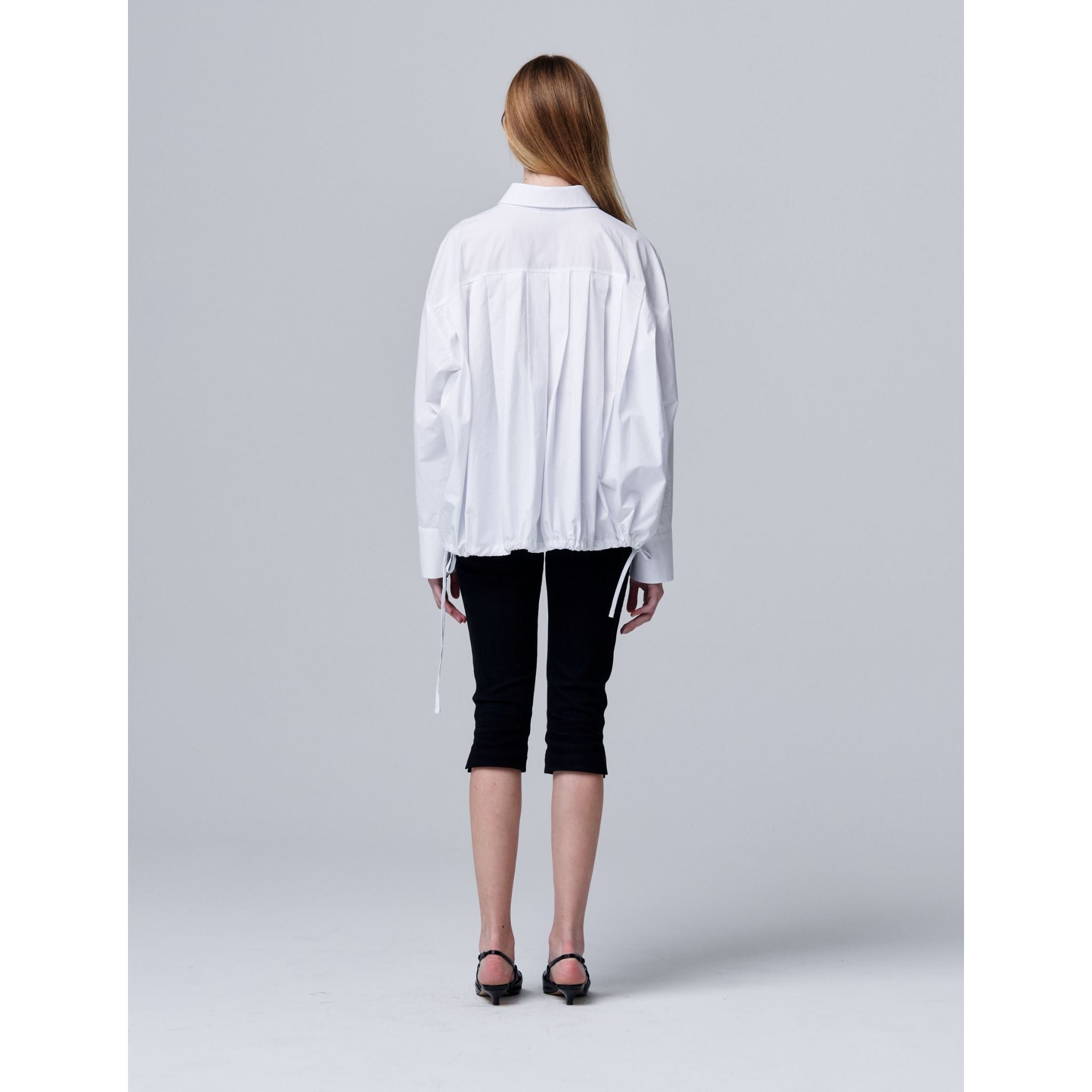 Person wearing a white shirt and black pants on a gray background