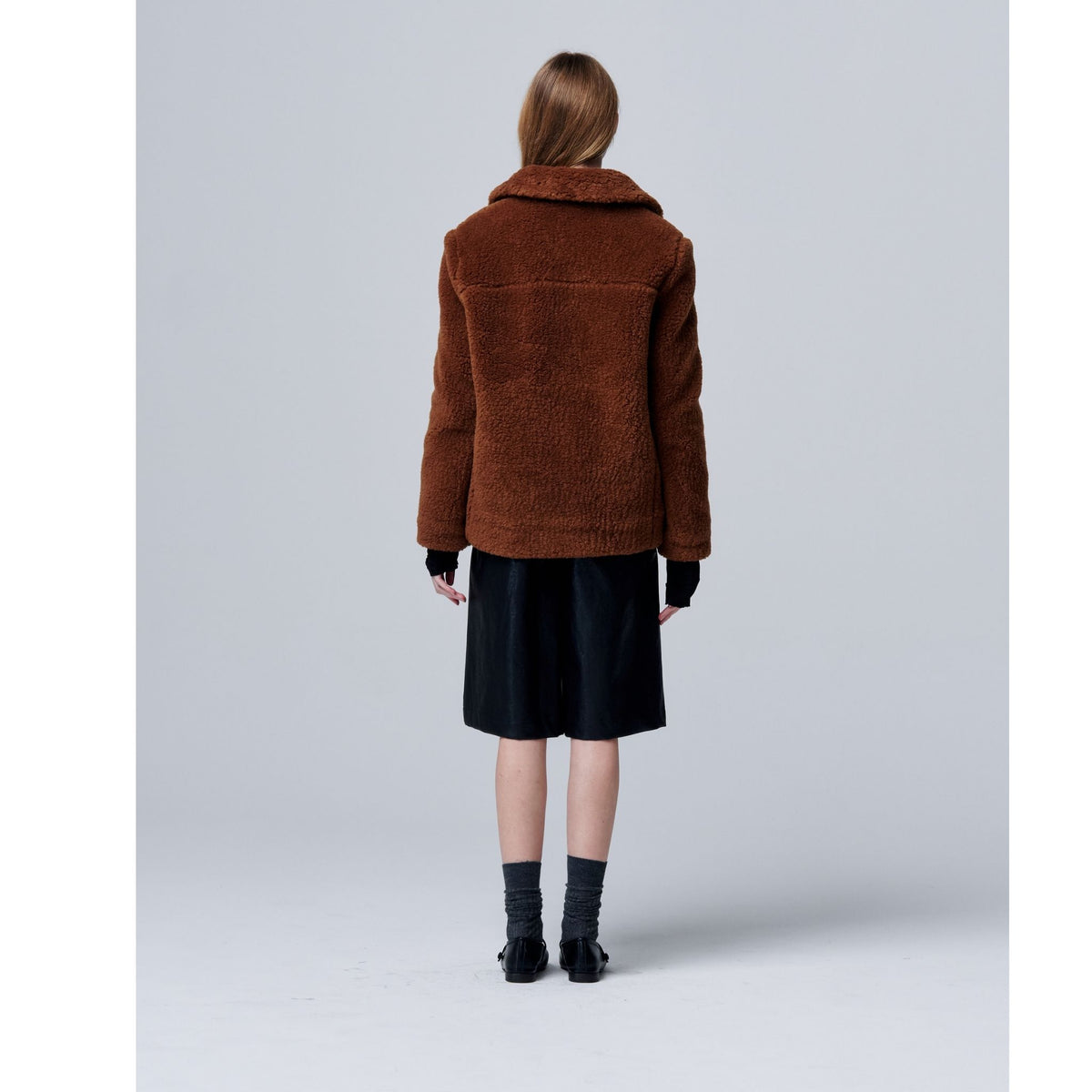 Person wearing a brown jacket on a light gray background