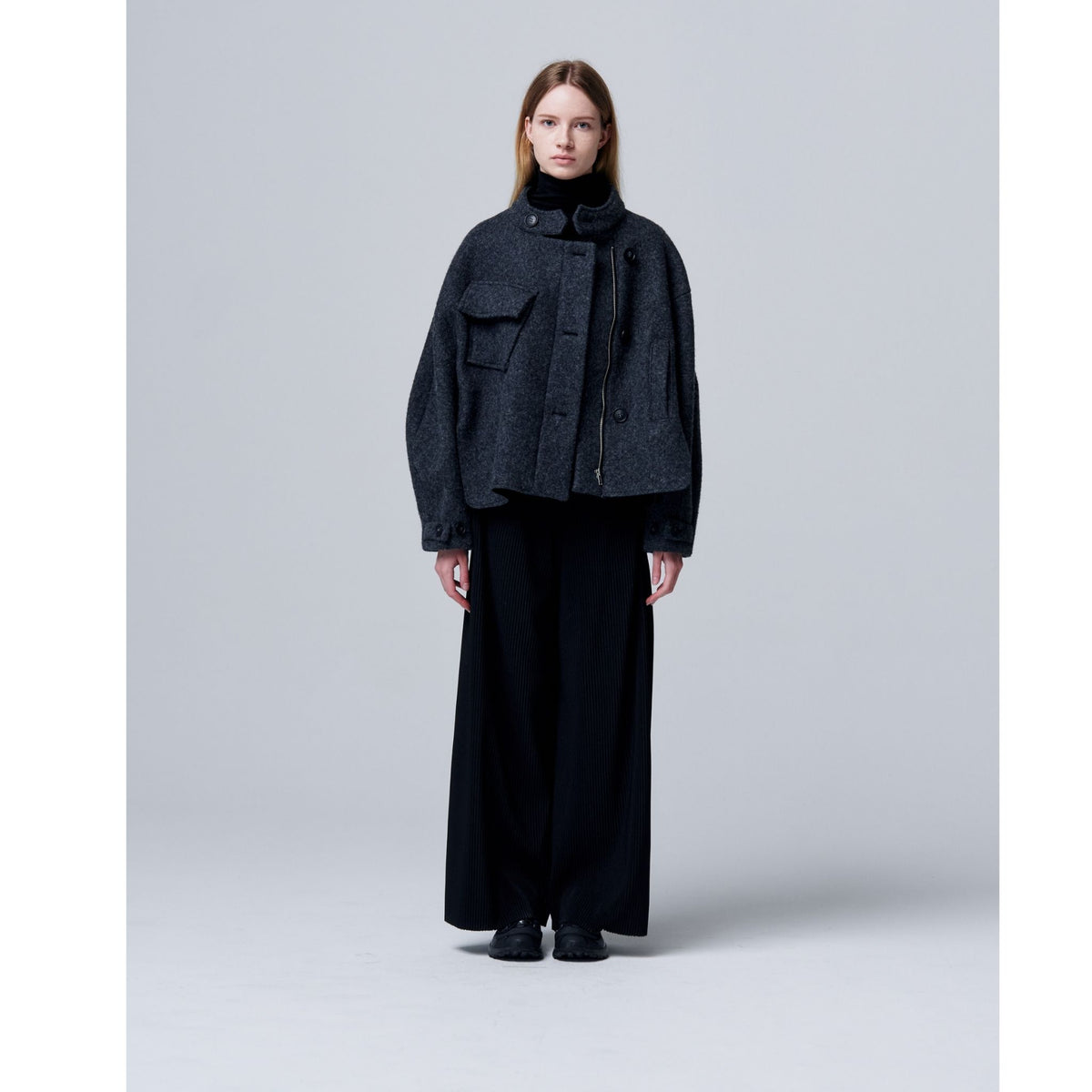 Person wearing a black outfit on a light gray background