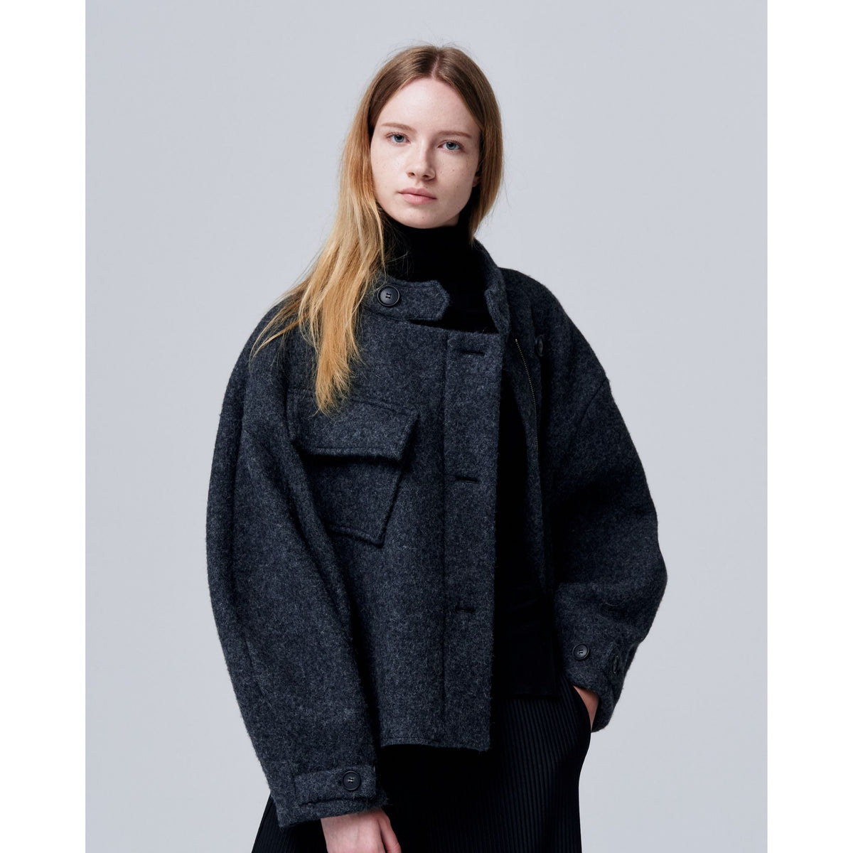 Person wearing a dark gray coat against a light gray background