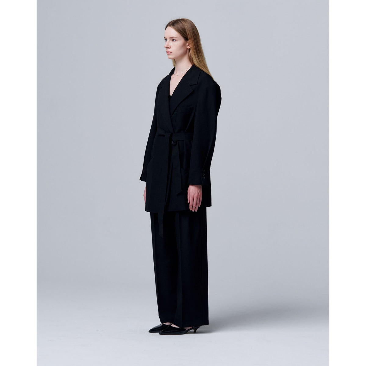 Woman wearing a black suit standing against a plain background