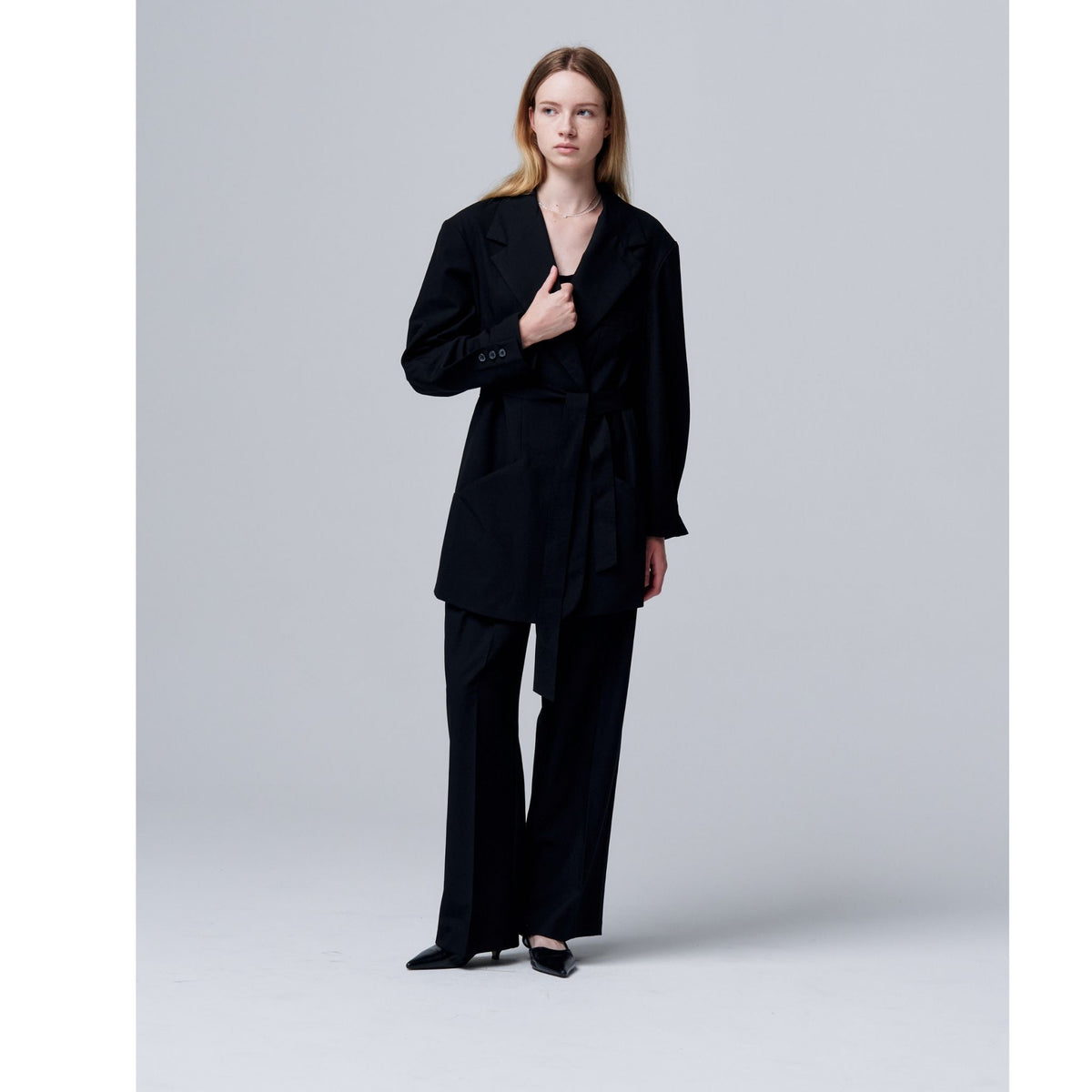 Woman wearing a black suit on a light gray background