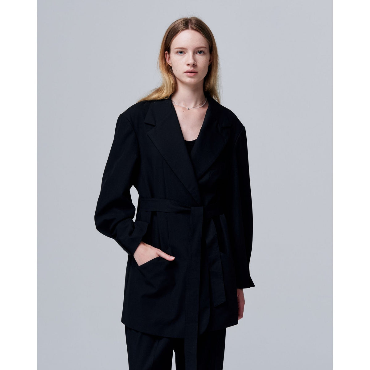 Woman wearing a black coat against a plain background