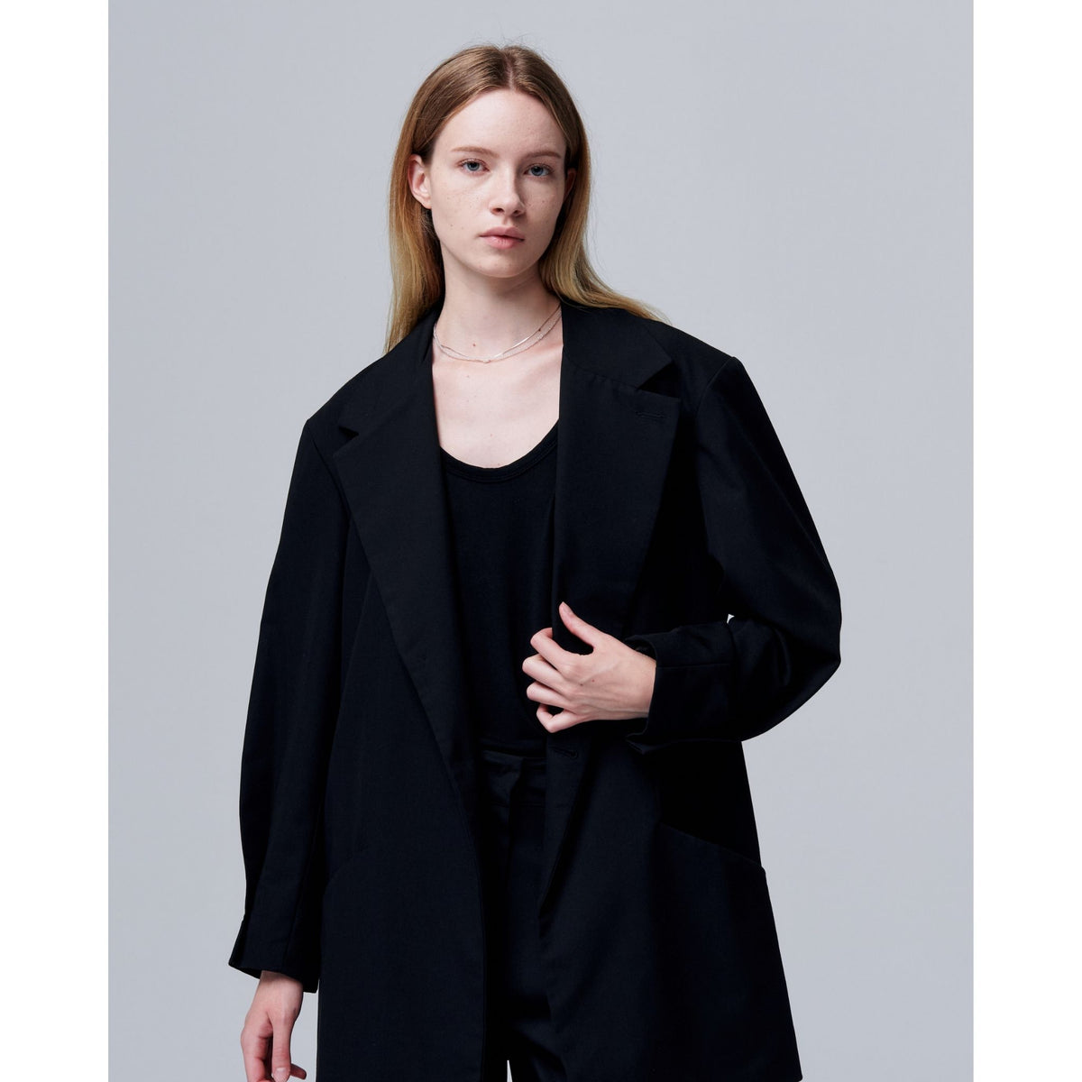 Woman wearing a black coat against a gray background