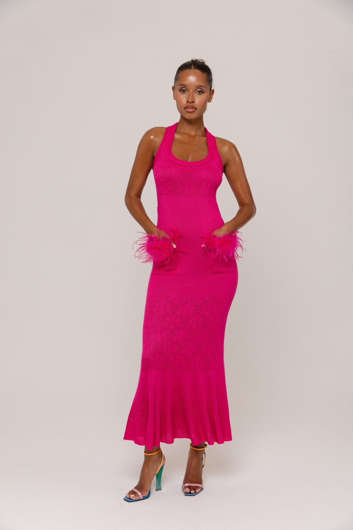 Woman wearing a  fuchsia dress with feather details on a white background