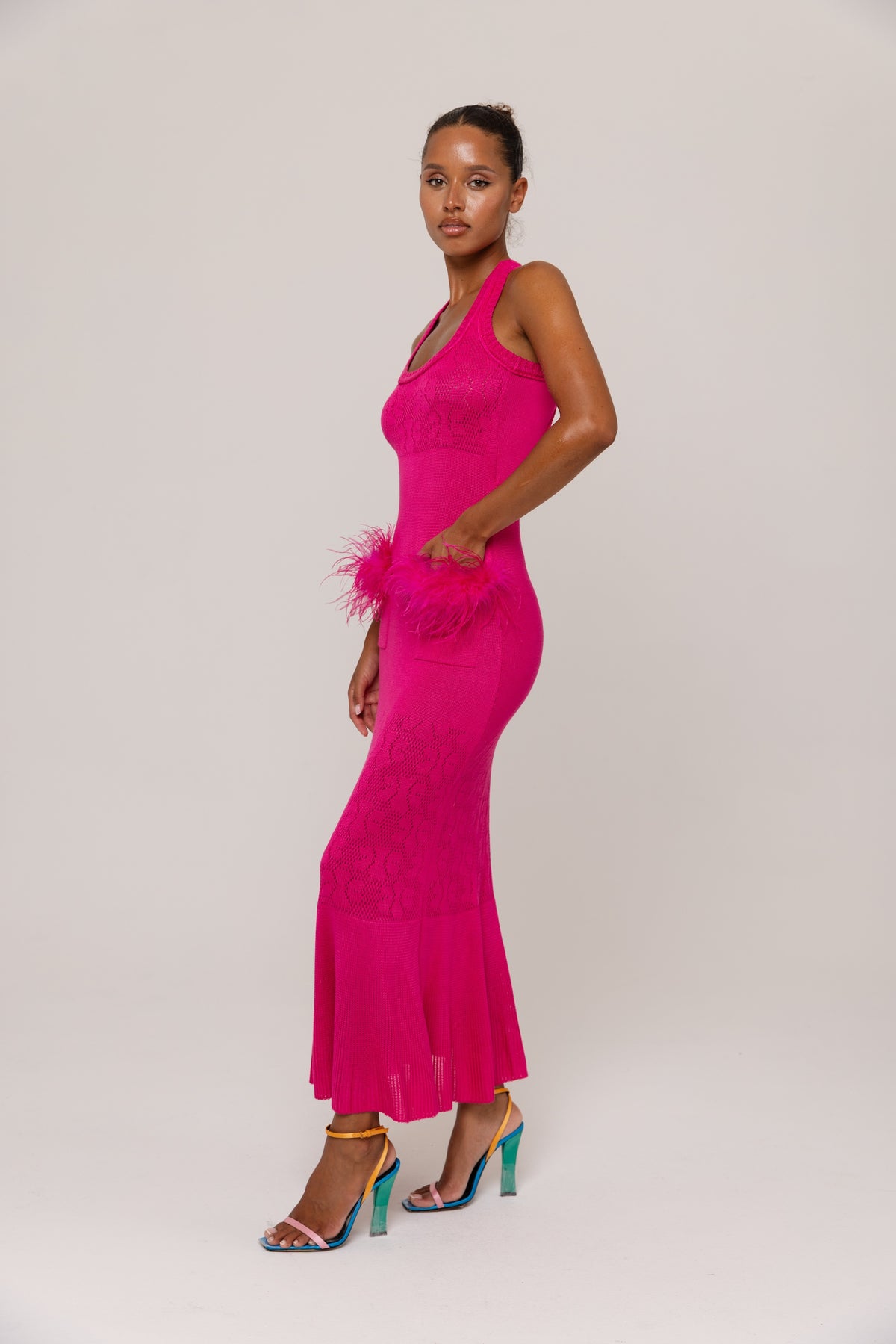 Woman wearing a  fuchsia dress with feather details on a white background