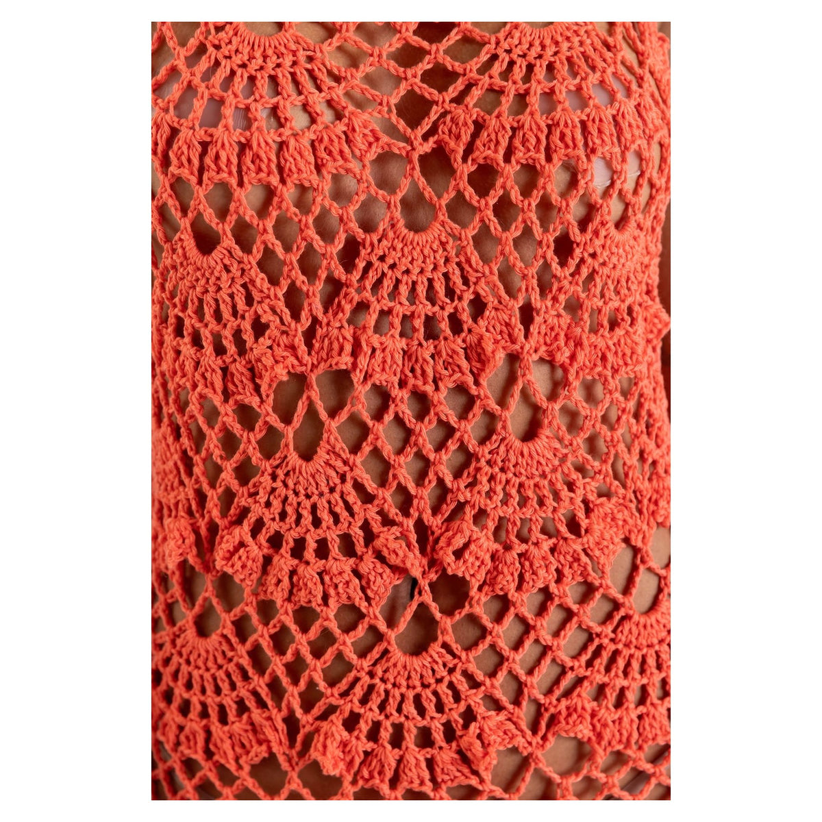 Close-up of the ANDREEVA Coral Shell Handmade Maxi Crochet Dress, showcasing its intricate orange crochet fabric with open, lacy shell and fan patterns that add a touch of coastal elegance.