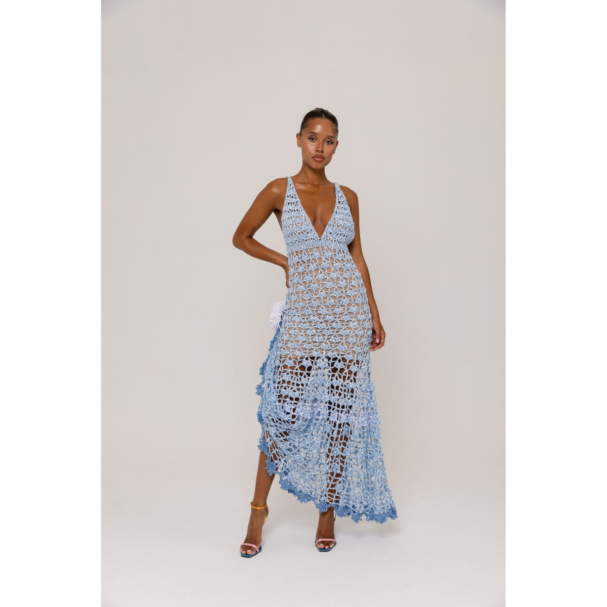 Woman wearing a light blue crochet dress on a plain background