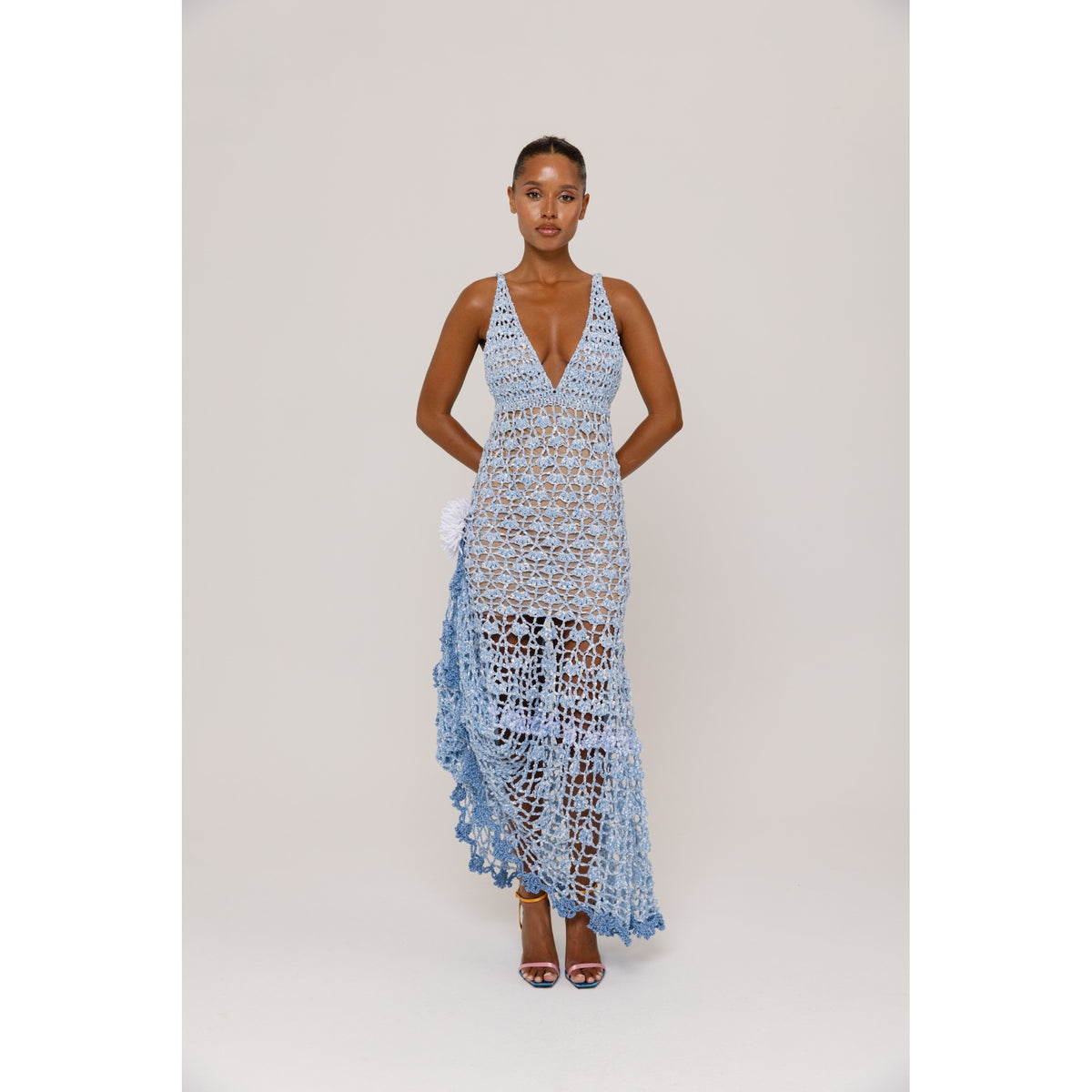 Woman wearing a blue crochet dress on a plain background