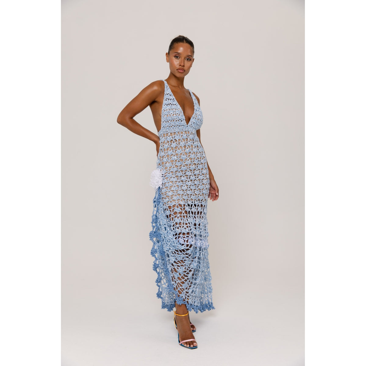 Woman wearing a blue crochet dress against a plain background