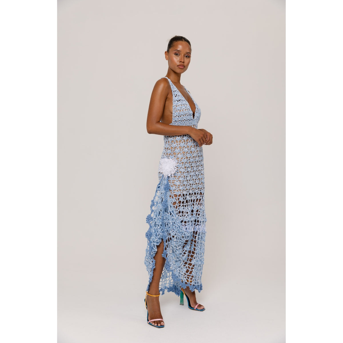 Woman wearing a blue crochet dress with floral details on a white background