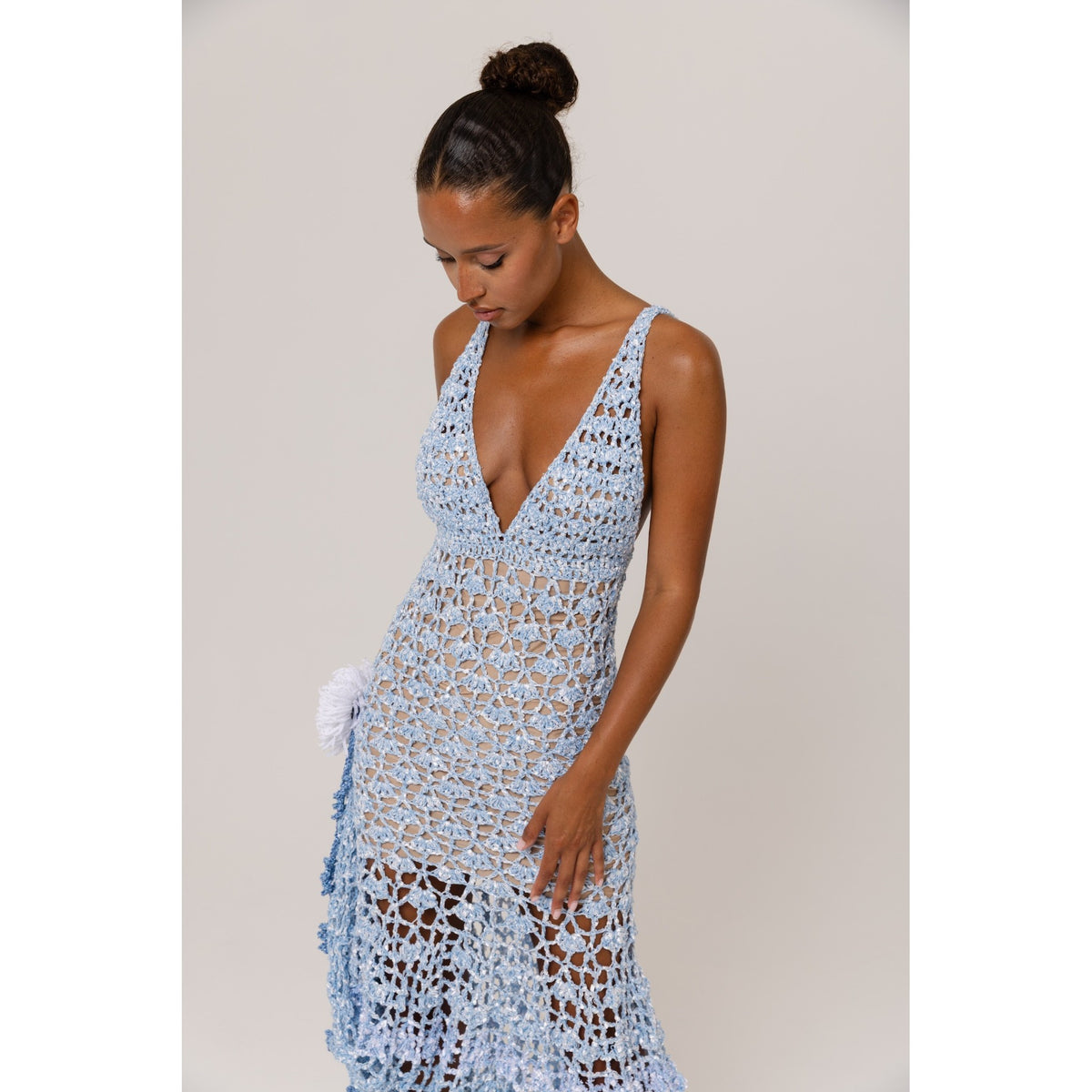 Woman wearing a light blue crochet dress against a plain background