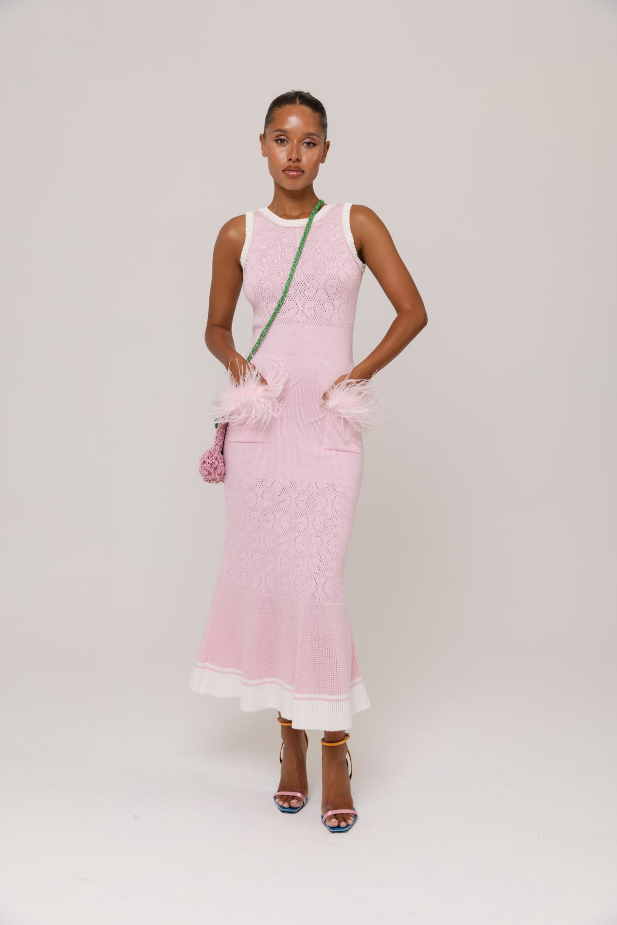 Woman wearing a pink dress with white trim on a plain background