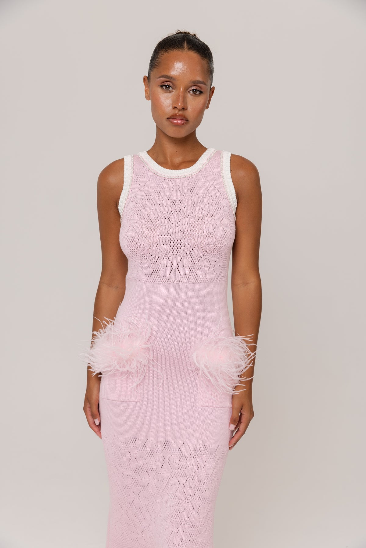 Woman wearing a pink lace dress with white accents on a plain background