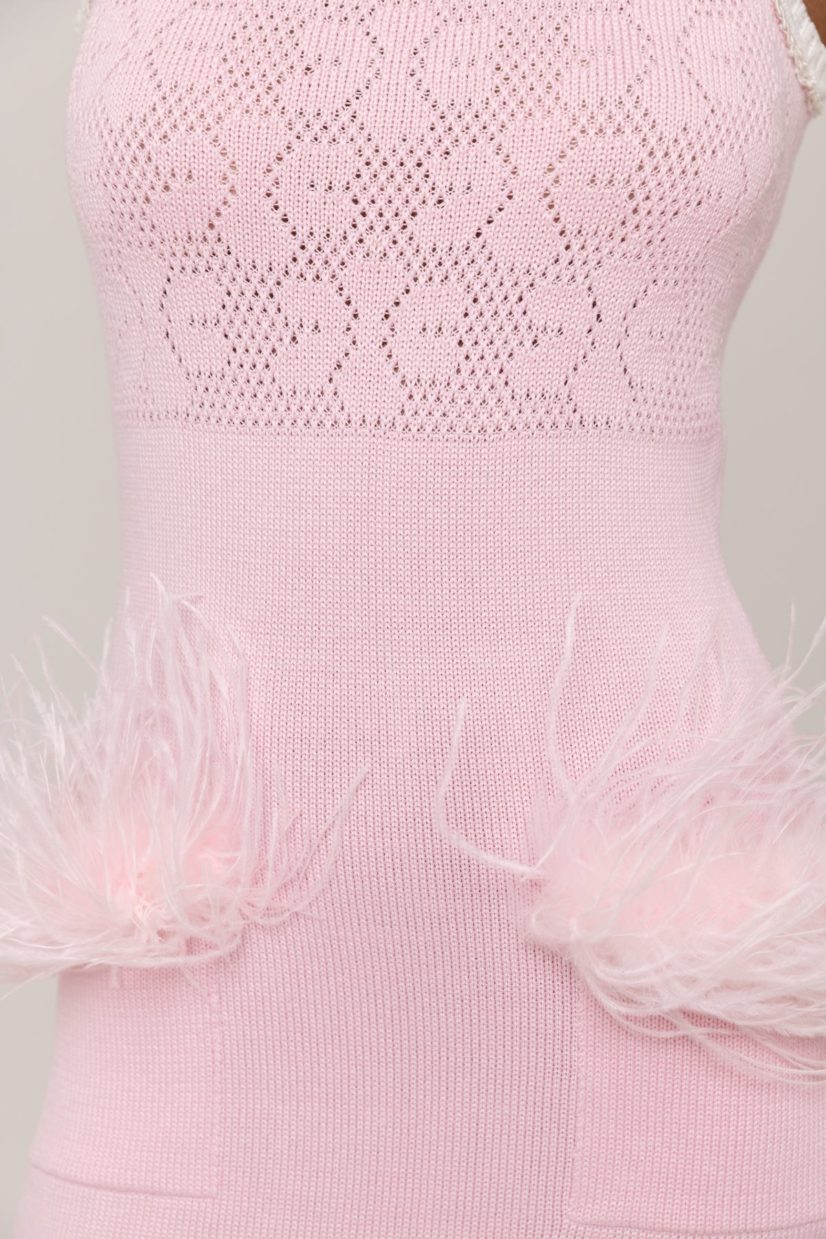 Pink dress with textured top and feathered hem on a light gray background