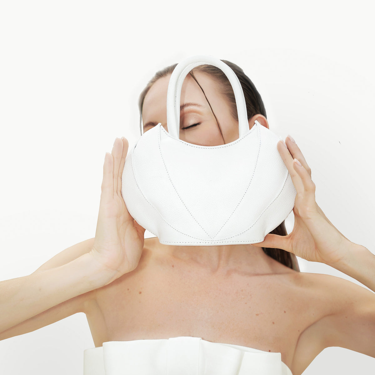 Model covering her face with the Etherea mini White 
