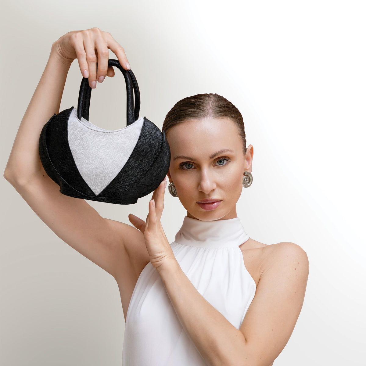 .Model wearing white dress with the Etherea mini black and White