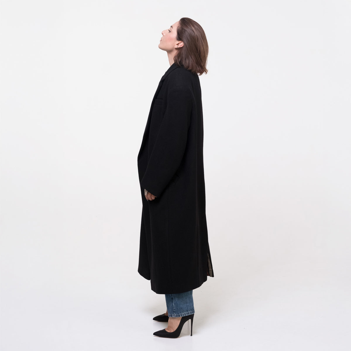 Woman wearing a long black coat on a white background