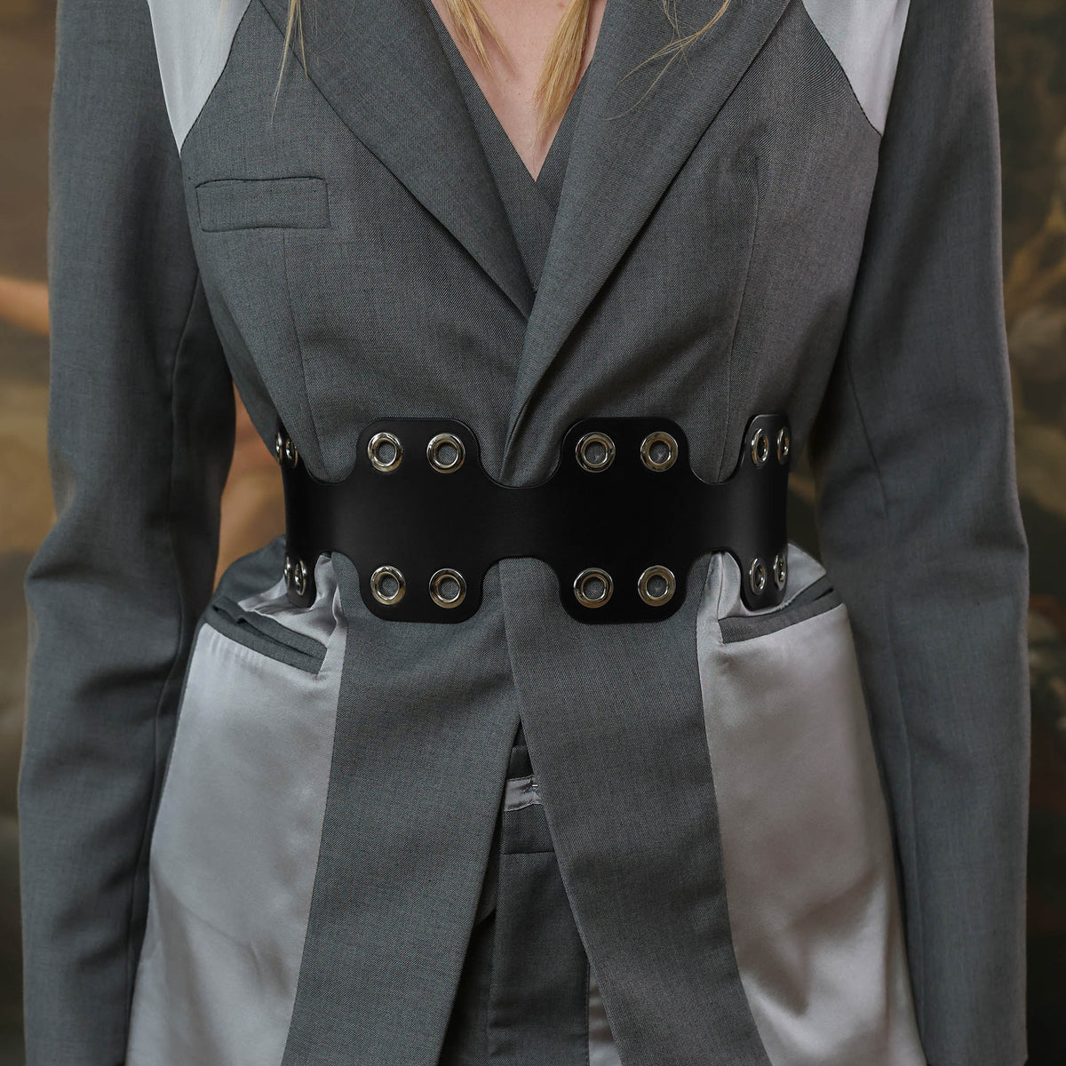 Gray suit with a black belt featuring silver buttons on a blurred background