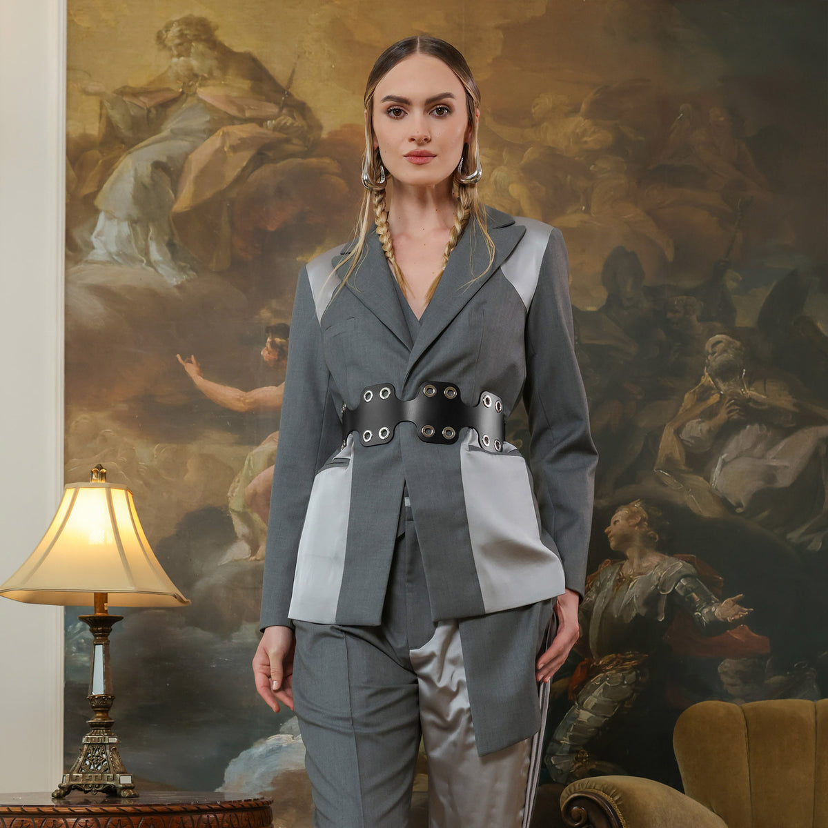 Woman in a gray outfit standing in front of an ornate painting