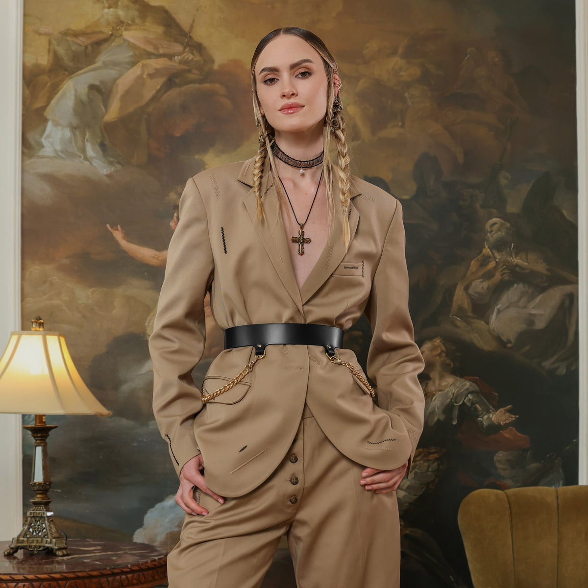 Woman in a beige suit standing in a room with a painting in the background